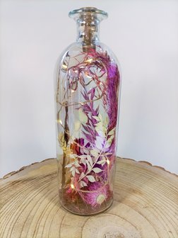Grote fles met droogbloemen en verlichting