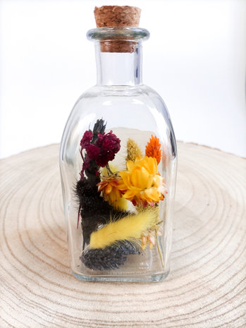Parfumfles gevuld met droogbloemen in geel rood en zwart