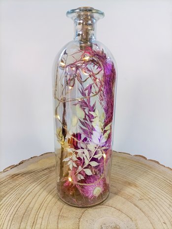 Grote fles met droogbloemen en verlichting